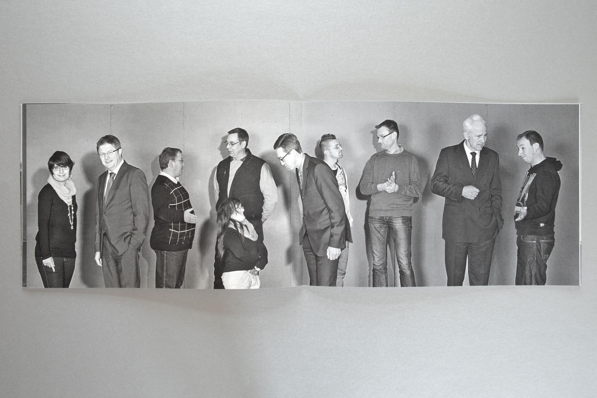 Das Foto auf einer Doppelseite zeigt zehn Personen der sozialen Allianz: Unternehmer und Gehandicapte im Gespräch.