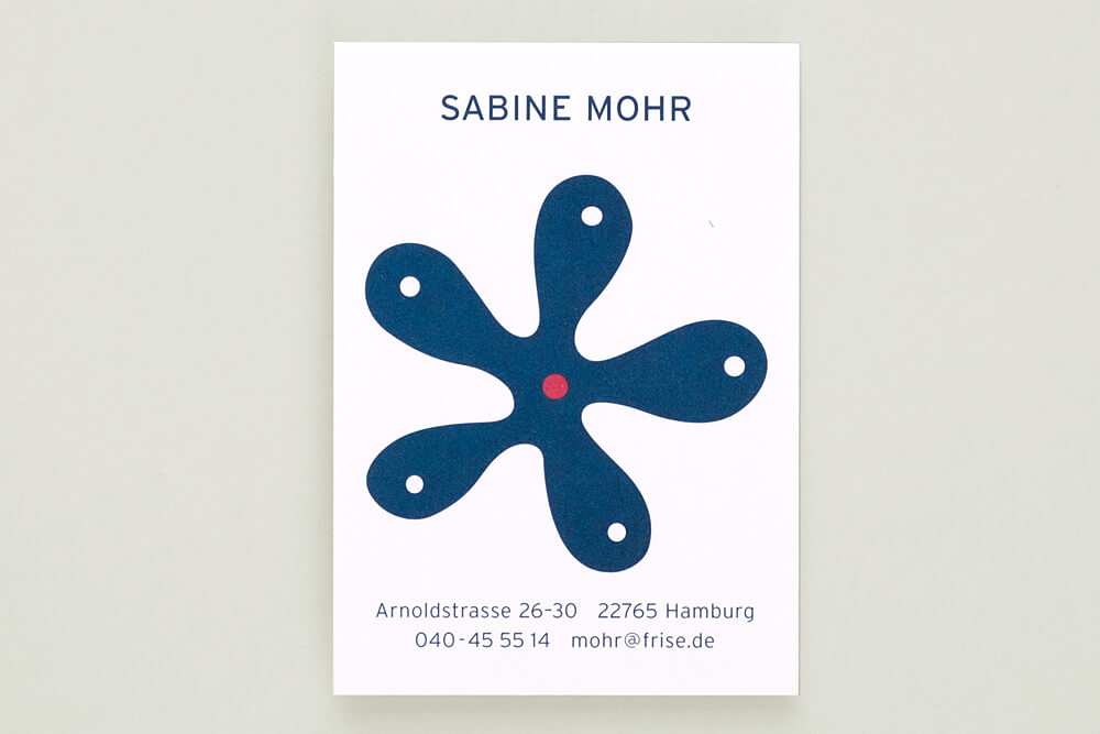 Vorschaubild: Foto einer Visitenkarte mit einem Logo in Form einer abstrakten fünf-fingrigen blauen Blume.