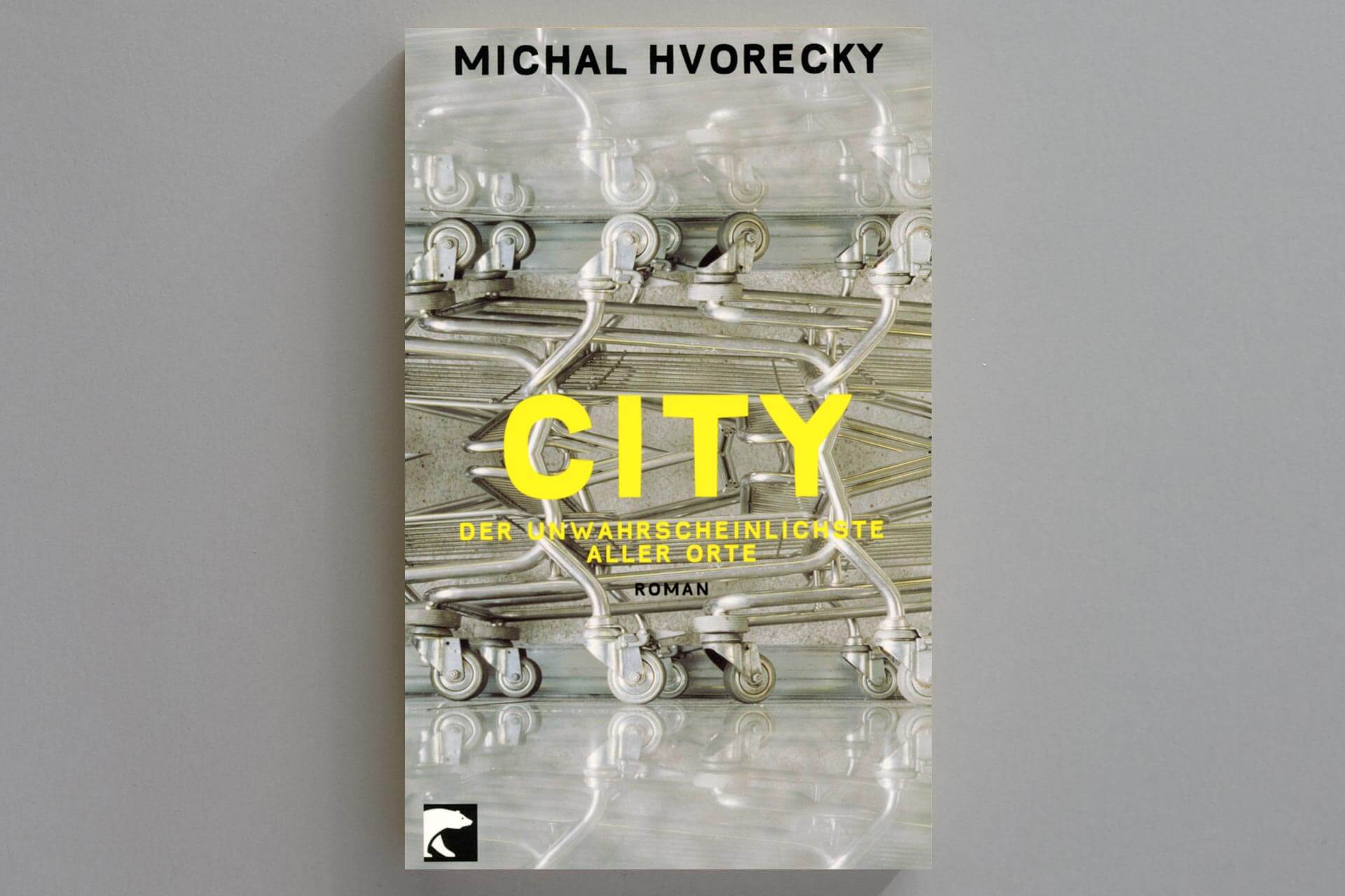 Abbildung einer Buchcover-Gestaltung für Michal Hvorecky’s „City“. Gelbe Typo auf Foto mit ornamentalem Einkaufswagen-Motiv.