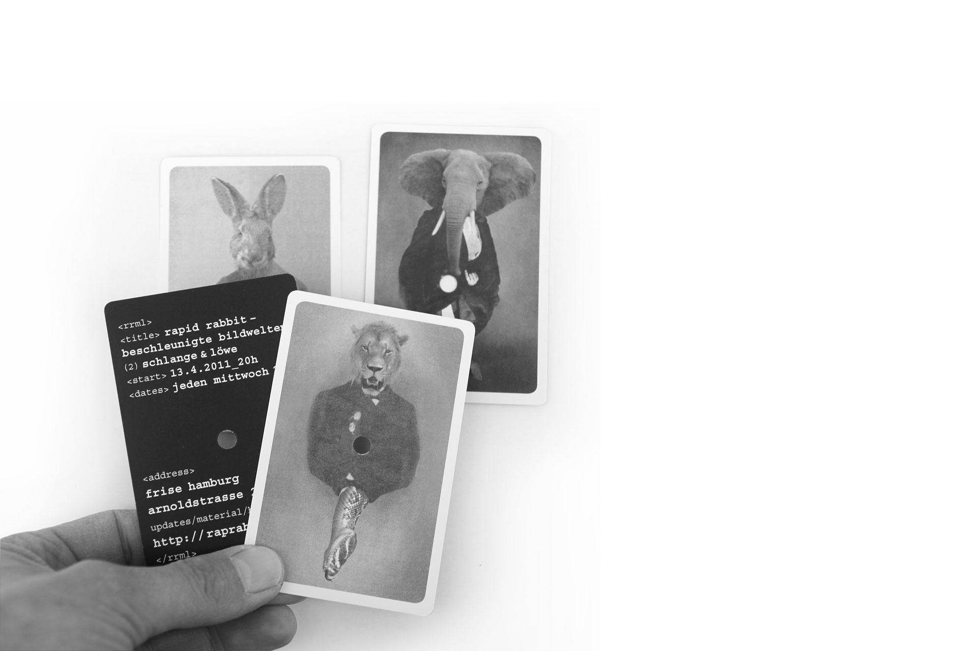 Foto von vier perforierten Einladungskarten im Spielkartenformat mit Tiermotiven von M. Meyer. Rückseiten mit Info-Text auf schwarzem Fond.
