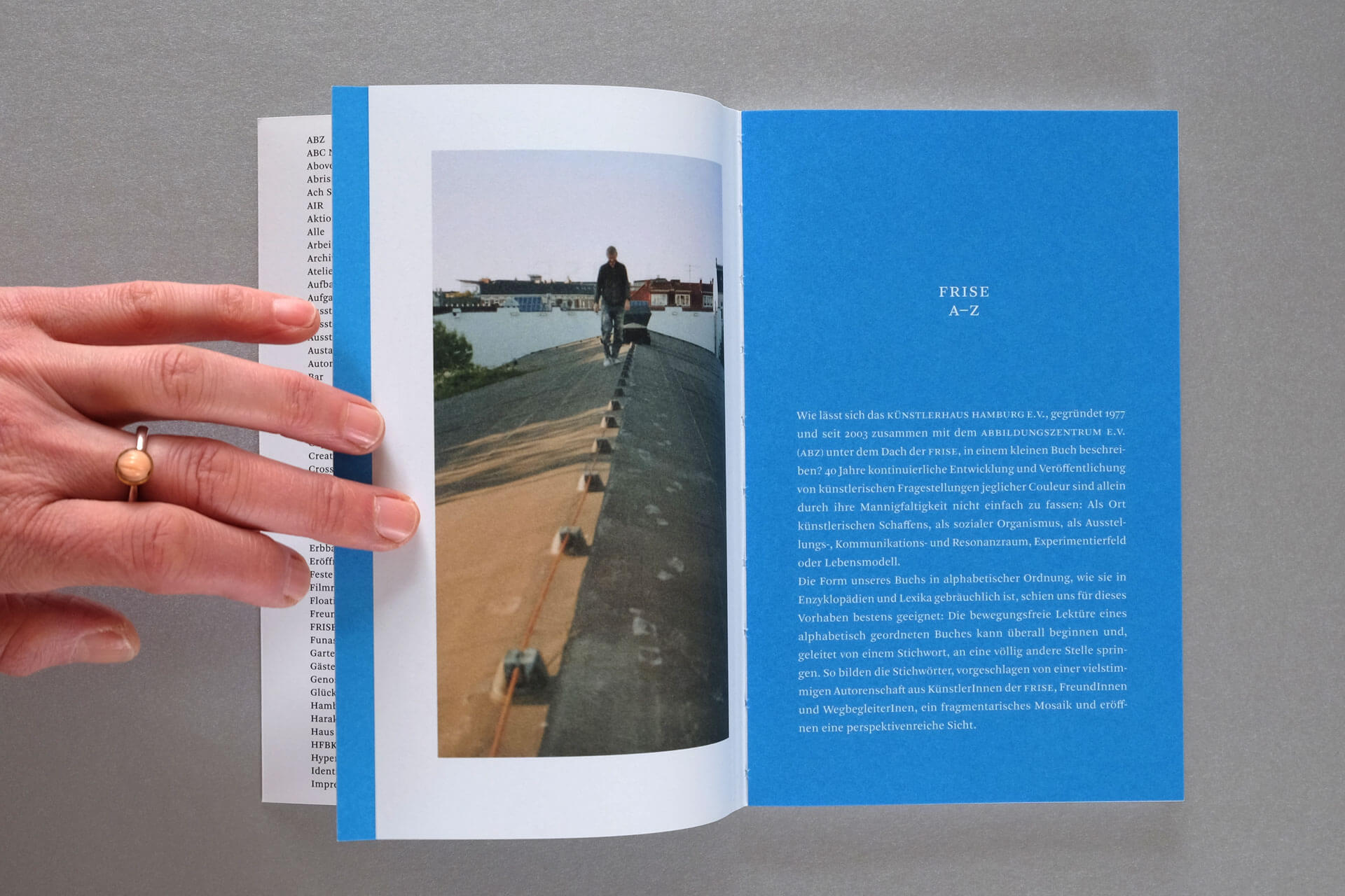 Publikation Frise A–Z. Links: Foto mit Mensch auf Dach. Rechts: Einleitungs-Text in weiß auf blauem Fond