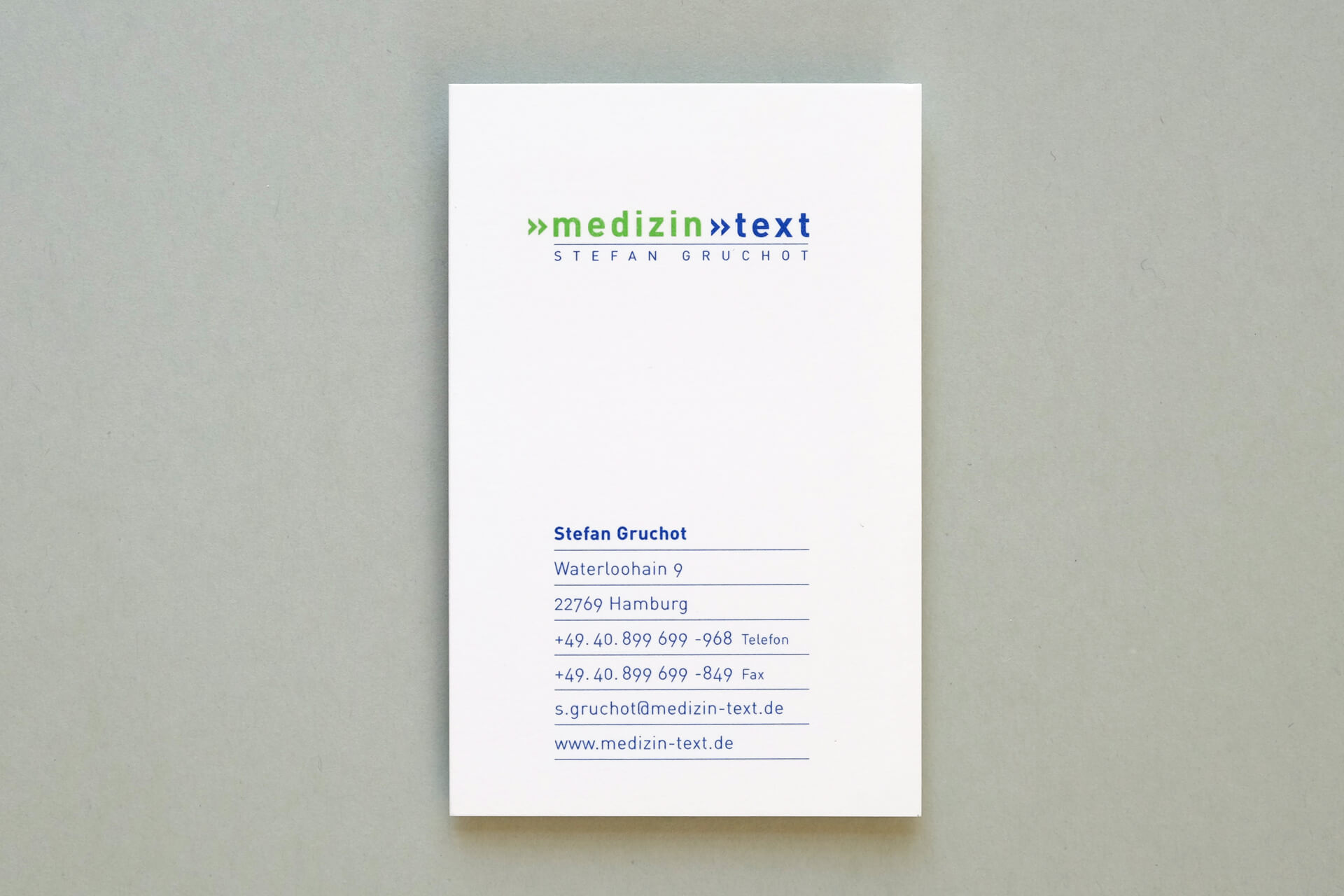 Foto der gedruckten Visitenkarte für „medizin-text“. Typographie in blau und grün