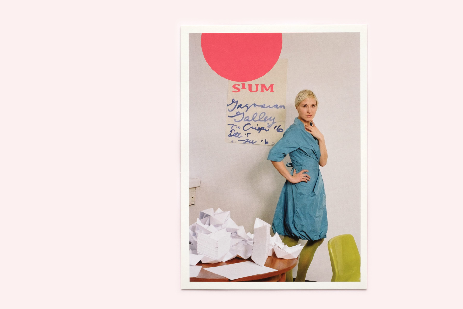 Postkarte mit Foto einer Frau die Sium-Mode trägt und Tisch mit gefalteten Schiffchen.